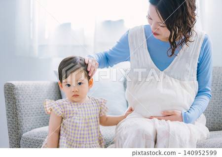 A little girl and her pregnant mother playing in the living room. A little girl and her pregnant mother playing in the living room. 140952599