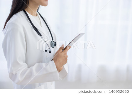 特寫：一位女醫生的手拿著一個活頁夾，站在窗邊。 140952660