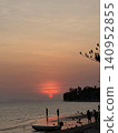 A tropical sea where a bright red sun sets. 140952855