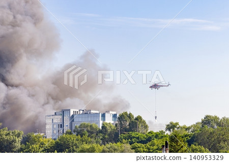 Helicopter drops water on building fire in city during daytime Helicopter drops water on building fire in city during daytime 140953329