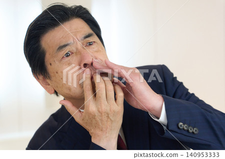 A businessman checks his nose hairs in the restroom. A businessman checks his nose hairs in the restroom. 140953333