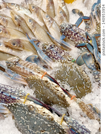 Fresh blue crabs and fish displayed on ice in market Fresh blue crabs and fish displayed on ice in market 140953954