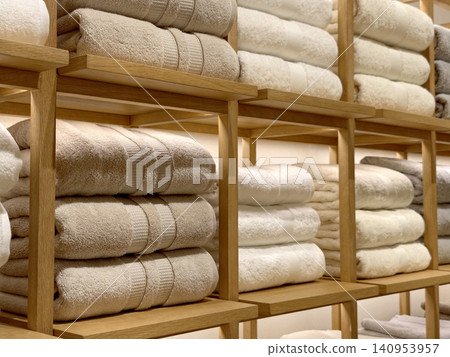 Neatly folded beige and white towels on wooden display shelves Neatly folded beige and white towels on wooden display shelves 140953957