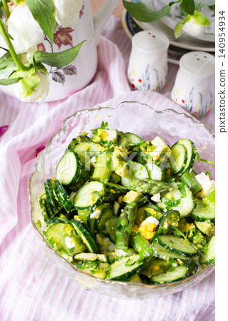 A bowl filled with cucumber salad features boiled eggs, asparagus, and avocado mixed with fresh greens. The salad is made from organic vegetables harvested in summer A bowl filled with cucumber salad features boiled eggs, asparagus, and avocado mixed with fresh greens. The salad is made from organic vegetables harvested in summer 140954934