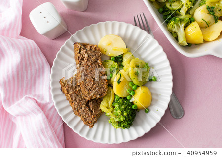 A plate holds boiled potatoes, turkey meat pie, broccoli, and green peas. This breakfast is healthy and gluten free, perfect for a good start to the day A plate holds boiled potatoes, turkey meat pie, broccoli, and green peas. This breakfast is healthy and gluten free, perfect for a good start to the day 140954959