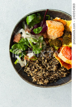 A quinoa bowl is filled with baked salmon, broccoli, tomatoes, and a fresh salad. This dish is good for breakfast or lunch and is rich in protein and nutrients A quinoa bowl is filled with baked salmon, broccoli, tomatoes, and a fresh salad. This dish is good for breakfast or lunch and is rich in protein and nutrients 140954969