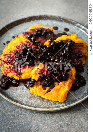 A plate holds millet pancakes topped with a rich currant sauce. The setting shows the food ready to be enjoyed at breakfast time. This meal is both healthy and gluten free A plate holds millet pancakes topped with a rich currant sauce. The setting shows the food ready to be enjoyed at breakfast time. This meal is both healthy and gluten free 140954980