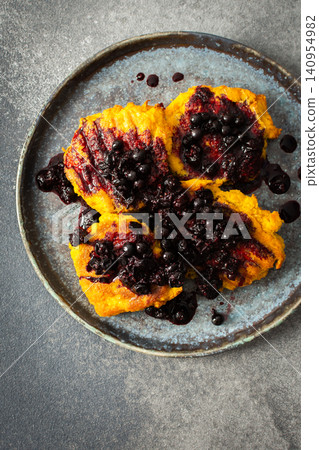 A plate holds millet pancakes topped with a rich currant sauce. The setting shows the food ready to be enjoyed at breakfast time. This meal is both healthy and gluten free A plate holds millet pancakes topped with a rich currant sauce. The setting shows the food ready to be enjoyed at breakfast time. This meal is both healthy and gluten free 140954982