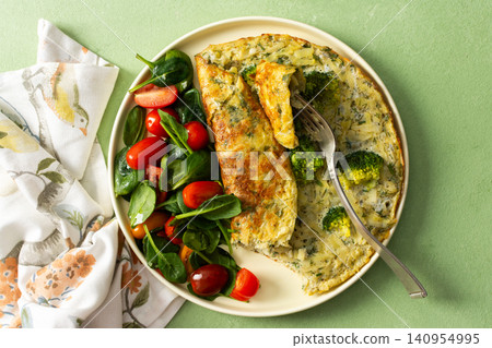 A plate holds a potato omelette made with eggs and filled with spinach and tomatoes. The meal looks fresh and healthy and is ideal for breakfast any day A plate holds a potato omelette made with eggs and filled with spinach and tomatoes. The meal looks fresh and healthy and is ideal for breakfast any day 140954995
