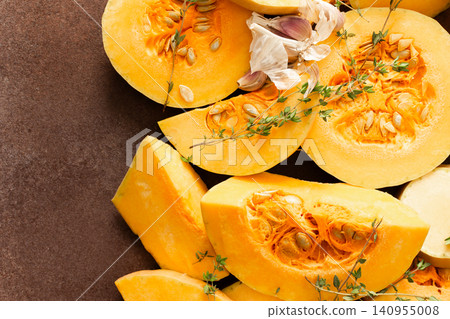 Pumpkin slices are arranged on a kitchen counter with fresh herbs nearby. The scene shows the preparation of seasonal dishes in the fall Pumpkin slices are arranged on a kitchen counter with fresh herbs nearby. The scene shows the preparation of seasonal dishes in the fall 140955008