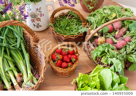 Baskets filled with freshly picked organic vegetables sit on a wooden table. Green onions, lettuce, and radishes are among the harvest from a local farm Baskets filled with freshly picked organic vegetables sit on a wooden table. Green onions, lettuce, and radishes are among the harvest from a local farm 140955009