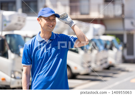 A truck and a smiling male delivery driver 140955063