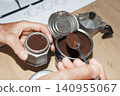 Filling Italian Moka Pot with Ground Coffee in Home Kitchen 140955067