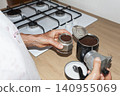 Filling Italian Moka Pot with Ground Coffee in Home Kitchen 140955069