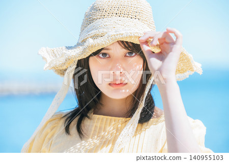 一位戴著草帽的女子凝望著大海。 140955103
