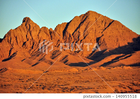 Iran, Iranian Plateau, near Tabas: Rocky mountains bathed in the red light of the setting sun. Iran, Iranian Plateau, near Tabas: Rocky mountains bathed in the red light of the setting sun. 140955518