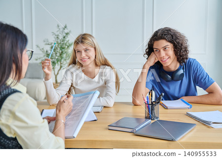 Smiling teenage students listening to female teacher Smiling teenage students listening to female teacher 140955533