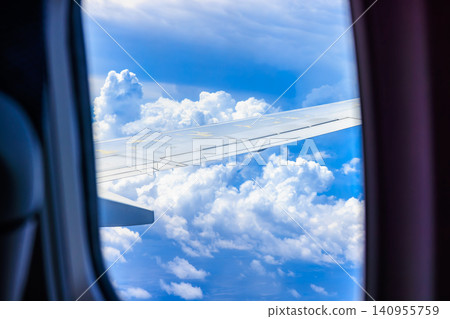 A vibrant blue sky and dynamic summer clouds viewed from the airplane window. A vibrant blue sky and dynamic summer clouds viewed from the airplane window. 140955759