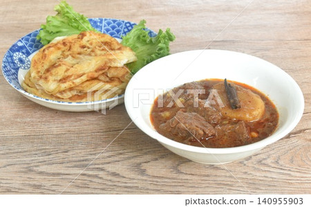 spicy beef meat massaman curry eat cuople with slice crispy roti and baby cos lecctue on bowl 140955903