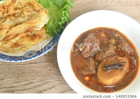 spicy beef meat massaman curry eat cuople with slice crispy roti and baby cos lecctue on bowl 140955904