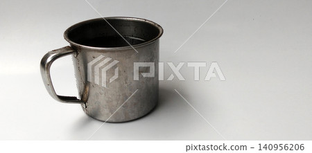 Insulated stainless steel mug containing black coffee, against a white background. 140956206