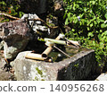 A bamboo water spout and a stone water basin in a Japanese garden. 140956268