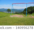 A swing on a grassy hill overlooking the mountains 140956278