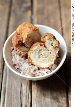 Large fried chicken pieces, cut in half, placed on top of rice. Large fried chicken pieces, cut in half, placed on top of rice. 140956358