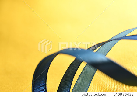Blue fabric ribbon on a yellow background Blue fabric ribbon on a yellow background 140956432