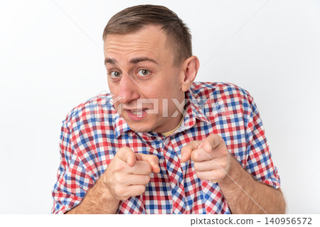 Young man wearing a plaid shirt looking and simultaneously pointing his index fingers directly at the viewer, conveying accusation, selection, demand, or engaging interaction Young man wearing a plaid shirt looking and simultaneously pointing his index fingers directly at the viewer, conveying accusation, selection, demand, or engaging interaction 140956572