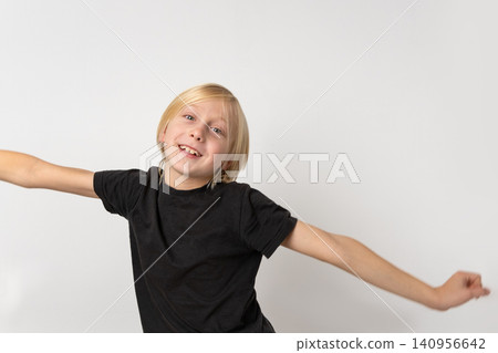 Energetic blonde boy with a missing front tooth smiles widely, spreading his arms out for play and expressing pure childhood joy against a plain white background Energetic blonde boy with a missing front tooth smiles widely, spreading his arms out for play and expressing pure childhood joy against a plain white background 140956642