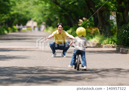 A father watches over his 2-year-old son riding a balance bike. A father watches over his 2-year-old son riding a balance bike. 140957322