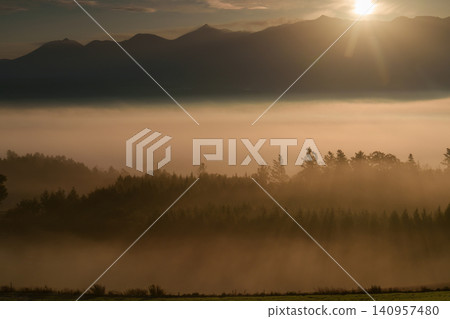 A breathtaking morning view of the Tokachi mountain range and sea of clouds from Senbo Pass in Kamifurano, Hokkaido. A fantastical and spectacular sight for tourists. A breathtaking morning view of the Tokachi mountain range and sea of clouds from Senbo Pass in Kamifurano, Hokkaido. A fantastical and spectacular sight for tourists. 140957480