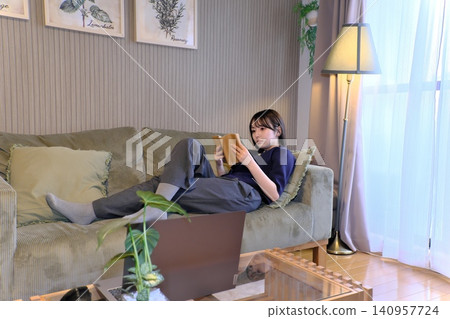 A blissful indoor holiday. Enjoying a book while bathed in soft light—a sophisticated adult relaxation time. A blissful indoor holiday. Enjoying a book while bathed in soft light—a sophisticated adult relaxation time. 140957724