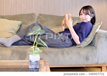 A blissful indoor holiday. Enjoying a book while bathed in soft light—a sophisticated adult relaxation time. A blissful indoor holiday. Enjoying a book while bathed in soft light—a sophisticated adult relaxation time. 140957732