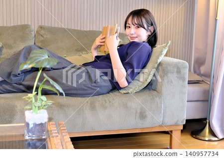 A blissful indoor holiday. Enjoying a book while bathed in soft light—a sophisticated adult relaxation time. A blissful indoor holiday. Enjoying a book while bathed in soft light—a sophisticated adult relaxation time. 140957734