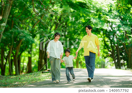 一家三口手牽手在公園散步。 140957792