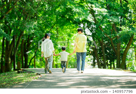 一家三口手牽手在公園散步。 140957796