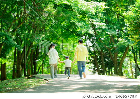 A family of three walking hand in hand in the park. A family of three walking hand in hand in the park. 140957797