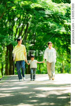 A family of three walking hand in hand in the park. A family of three walking hand in hand in the park. 140957800