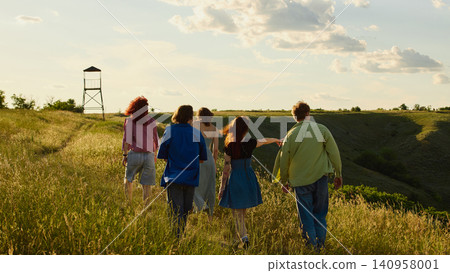 Back view of friends walking across countryside hills at golden hour Back view of friends walking across countryside hills at golden hour 140958001