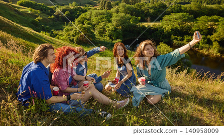 Friends taking selfie during picnic on scenic hill. Friends taking selfie during picnic on scenic hill. 140958009