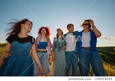 Young friends laughing together on sunny hillside in countryside. Young friends laughing together on sunny hillside in countryside. 140958056