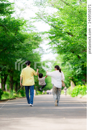 A family of three walking hand in hand in the park. A family of three walking hand in hand in the park. 140958071