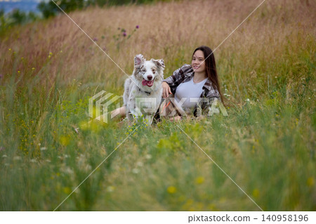 Happy dog running through wild meadow near resting owner. Happy dog running through wild meadow near resting owner. 140958196