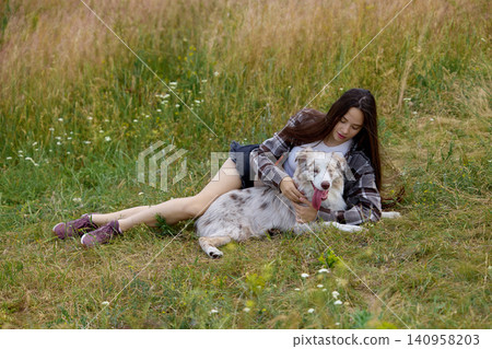 Woman resting with dog in summer meadow during countryside escape. Woman resting with dog in summer meadow during countryside escape. 140958203