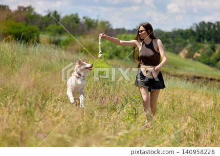 Woman playing with dog toy in open countryside field. Woman playing with dog toy in open countryside field. 140958228