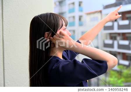 A smiling woman pointing happily on a balcony. A smiling woman pointing happily on a balcony. 140958246