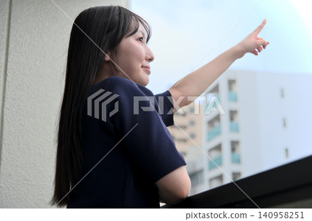 一位微笑的女子高興地指著陽台。 一位微笑的女子高興地指著陽台。 140958251