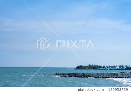 Coastal Sea Landscape with Wooden Breakwater Poles and Tropical Shoreline 140958769